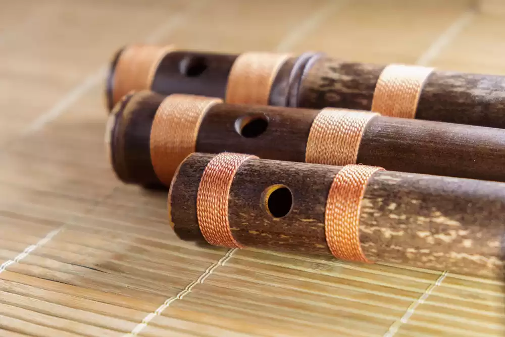 A set of three jinashi shakuhachi flutes on a bamboo mat