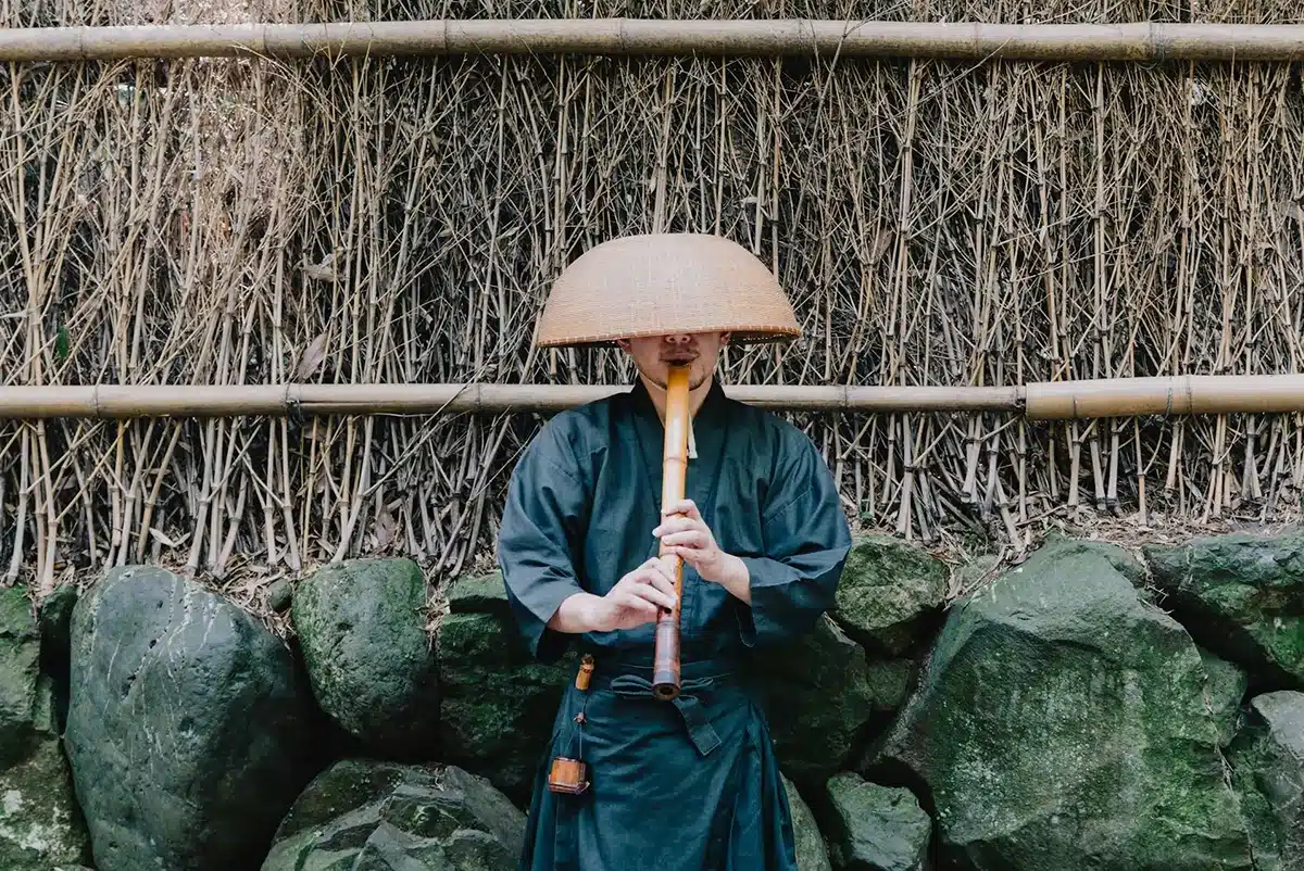 a traditional shakuhachi player in a kasa and kimono